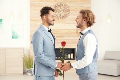 Happy newlywed gay couple with flower at home