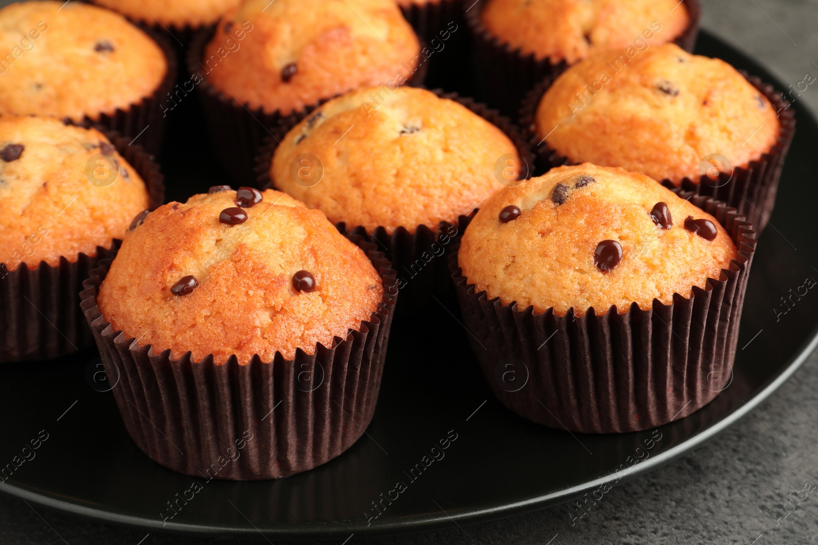 Photo of Delicious freshly baked muffins with chocolate chips on table, closeup