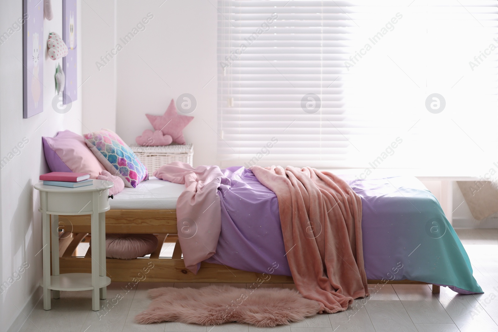 Photo of Bed with colorful linen in stylish children's room. Interior design