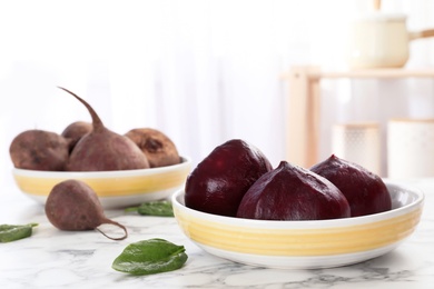 Photo of Bowl with ripe peeled beets on table