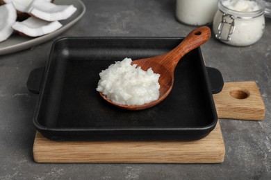 Baking dish with coconut oil and wooden spoon on grey table