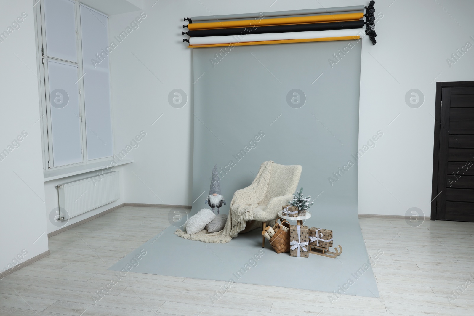 Photo of Stylish photo zone with armchair and Christmas decor in professional studio