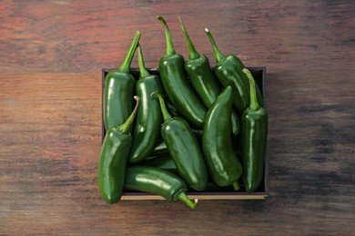 Photo of Crate with green jalapeno peppers on wooden table, top view