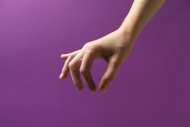 Photo of Woman holding something in hand on purple background, closeup