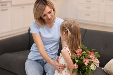 Little girl hiding bouquet of alstroemeria flowers for mom at home, selective focus. Happy Mother's Day