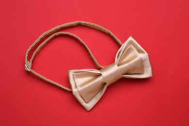 Photo of Stylish beige bow tie on red background, top view