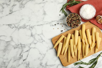 Photo of Fresh baby corn cobs and spices on white marble table, flat lay. Space for text