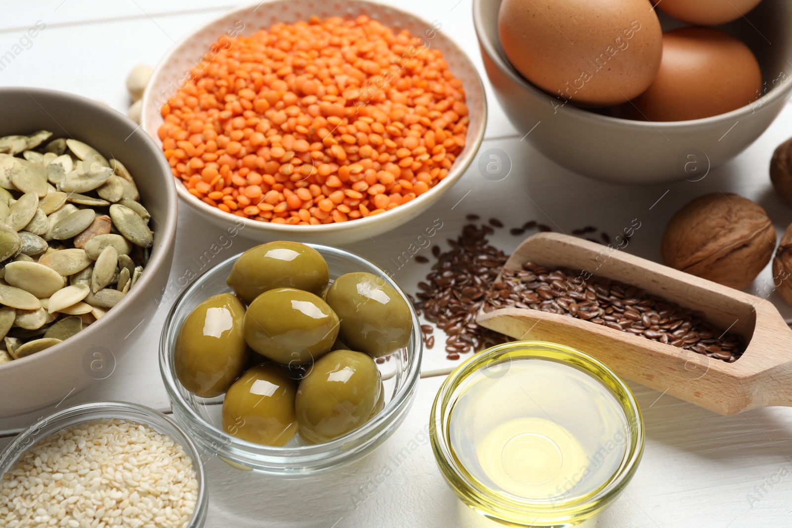 Photo of Different products high in natural fats on white wooden table, closeup