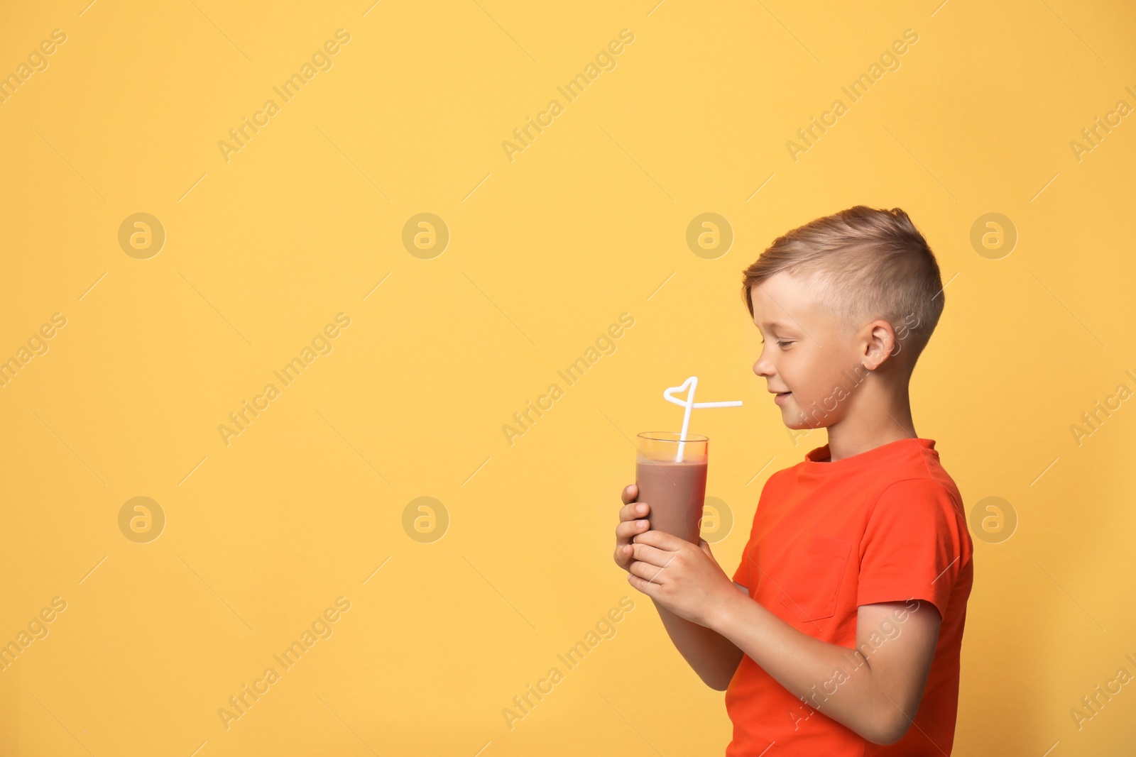 Photo of Little boy with glass of milk shake on color background