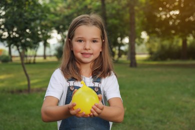 Cute little girl holding water bomb in park