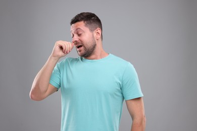 Photo of Allergy symptom. Man sneezing on light grey background