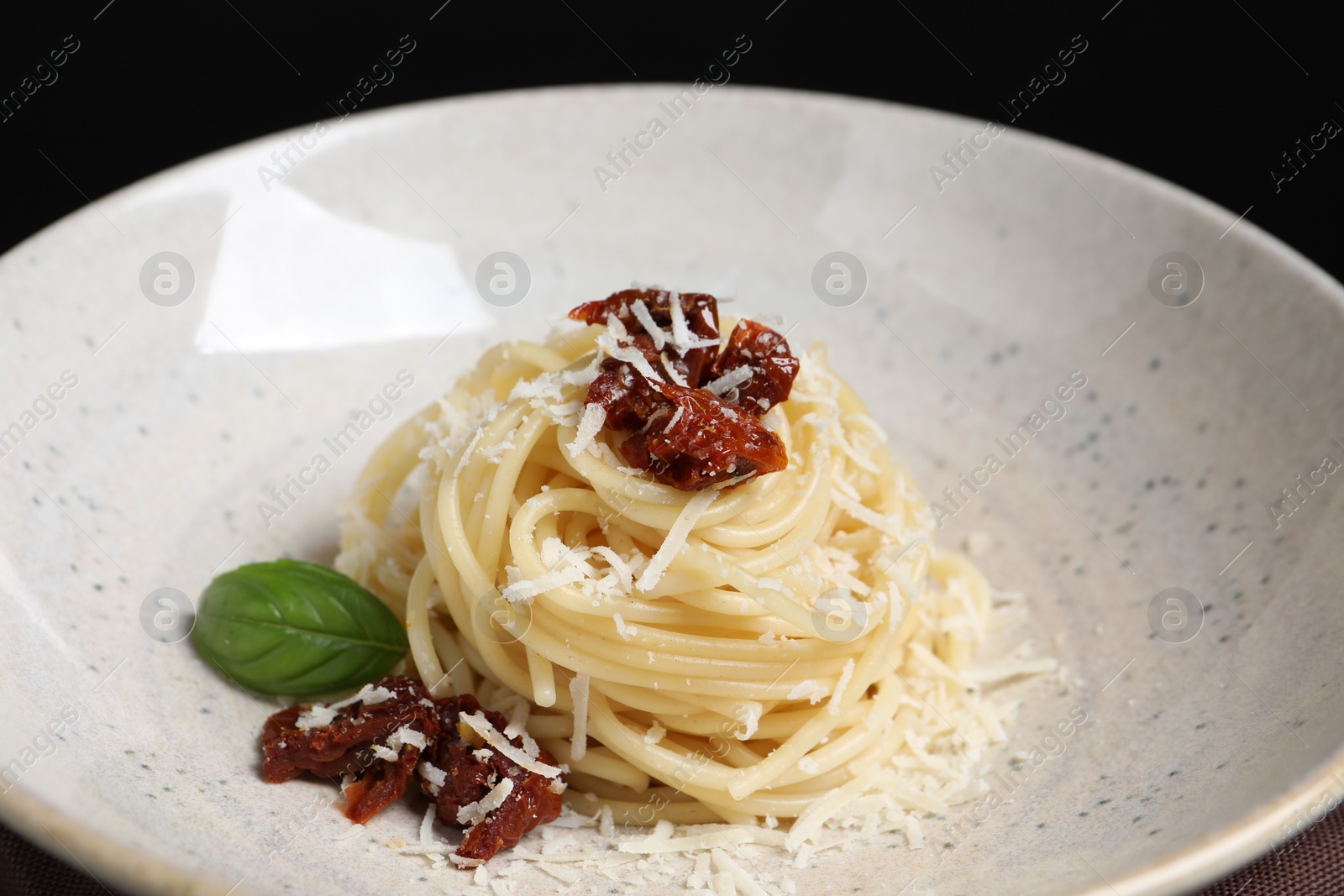 Photo of Tasty spaghetti with sun-dried tomatoes and parmesan cheese on plate, closeup. Exquisite presentation of pasta dish