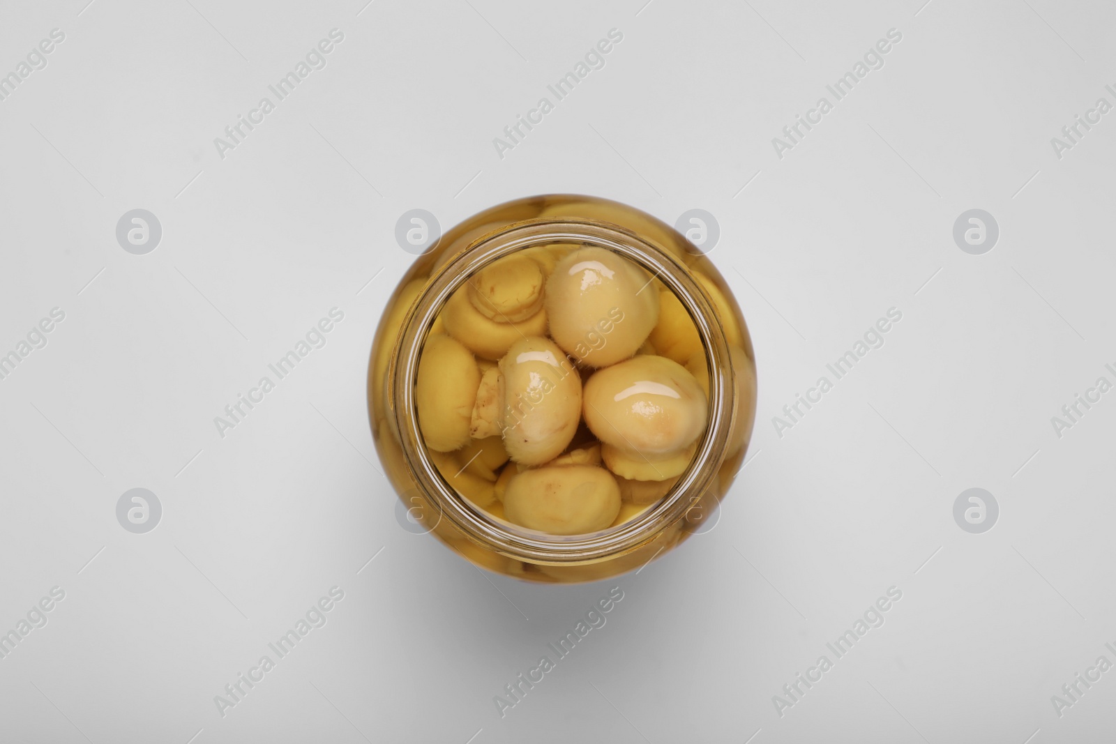 Photo of Jar of tasty pickled mushrooms on white background, top view