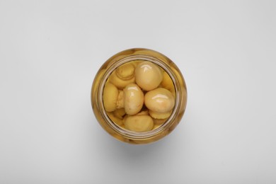 Photo of Jar of tasty pickled mushrooms on white background, top view