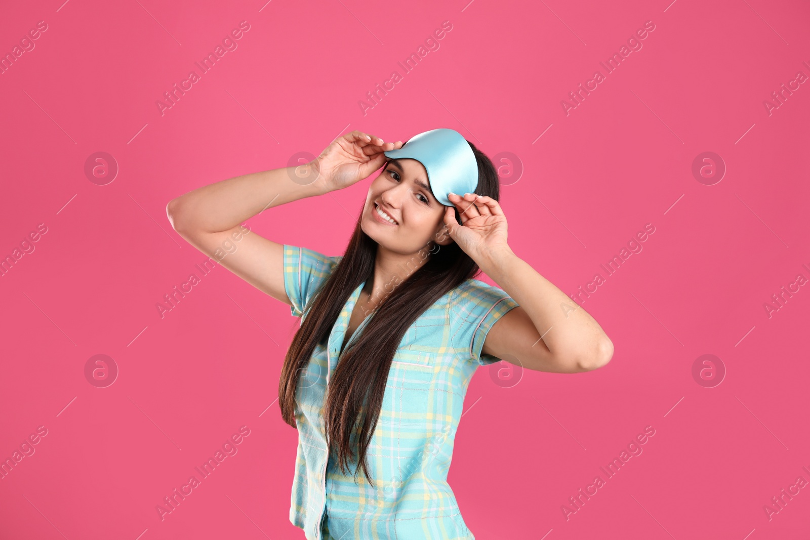 Photo of Beautiful woman wearing sleeping mask on pink background. Bedtime