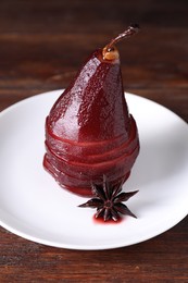 Tasty red wine poached pear and anise on wooden table, closeup