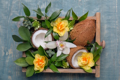 Photo of Box with coconuts and flowers on wooden background