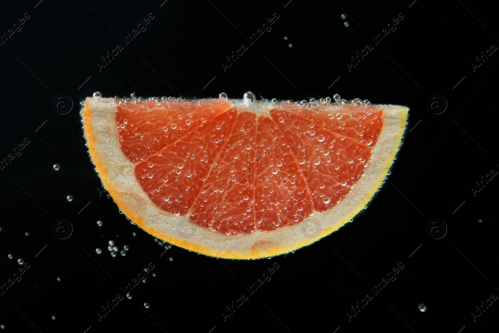 Photo of Slice of grapefruit in sparkling water on black background. Citrus soda