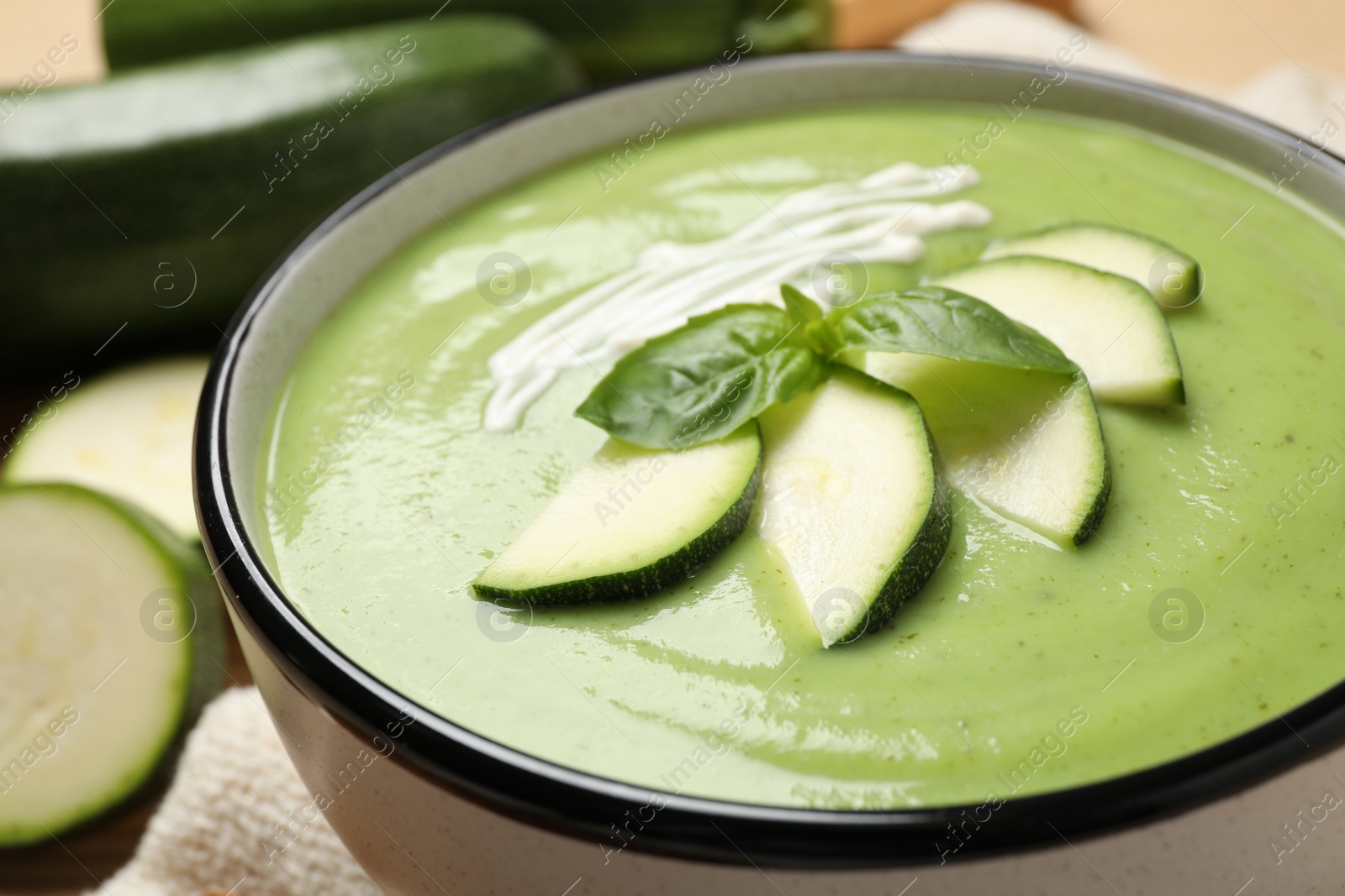 Photo of Tasty homemade zucchini cream soup in bowl, closeup