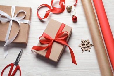 Flat lay composition with beautiful Christmas gift boxes and wrapping paper on white wooden table