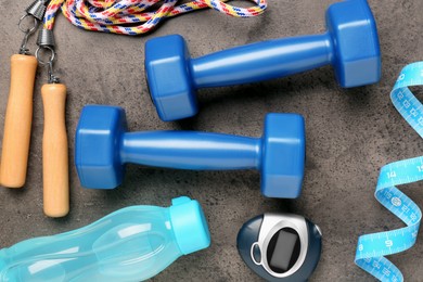 Photo of Flat lay composition with dumbbells on brown textured table