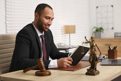 Smiling lawyer reading book at table in office