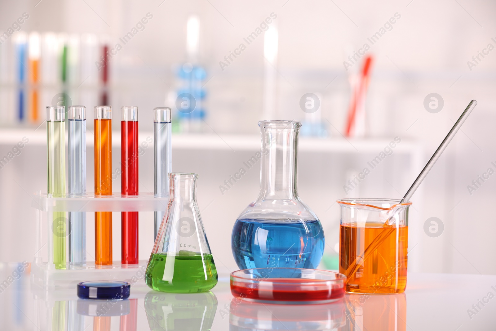 Photo of Laboratory analysis. Different glassware with liquids on white table against blurred background