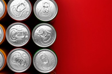 Energy drinks in wet cans on red background, top view. Space for text