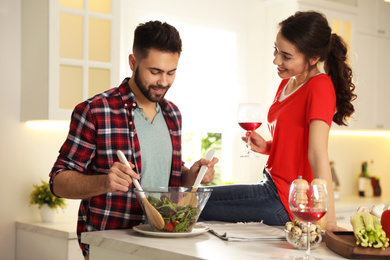 Photo of Lovely young couple cooking salad together in kitchen