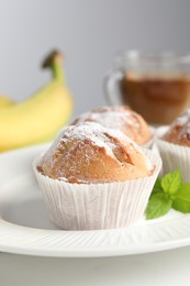Photo of Tasty muffins served with mint on white table, closeup