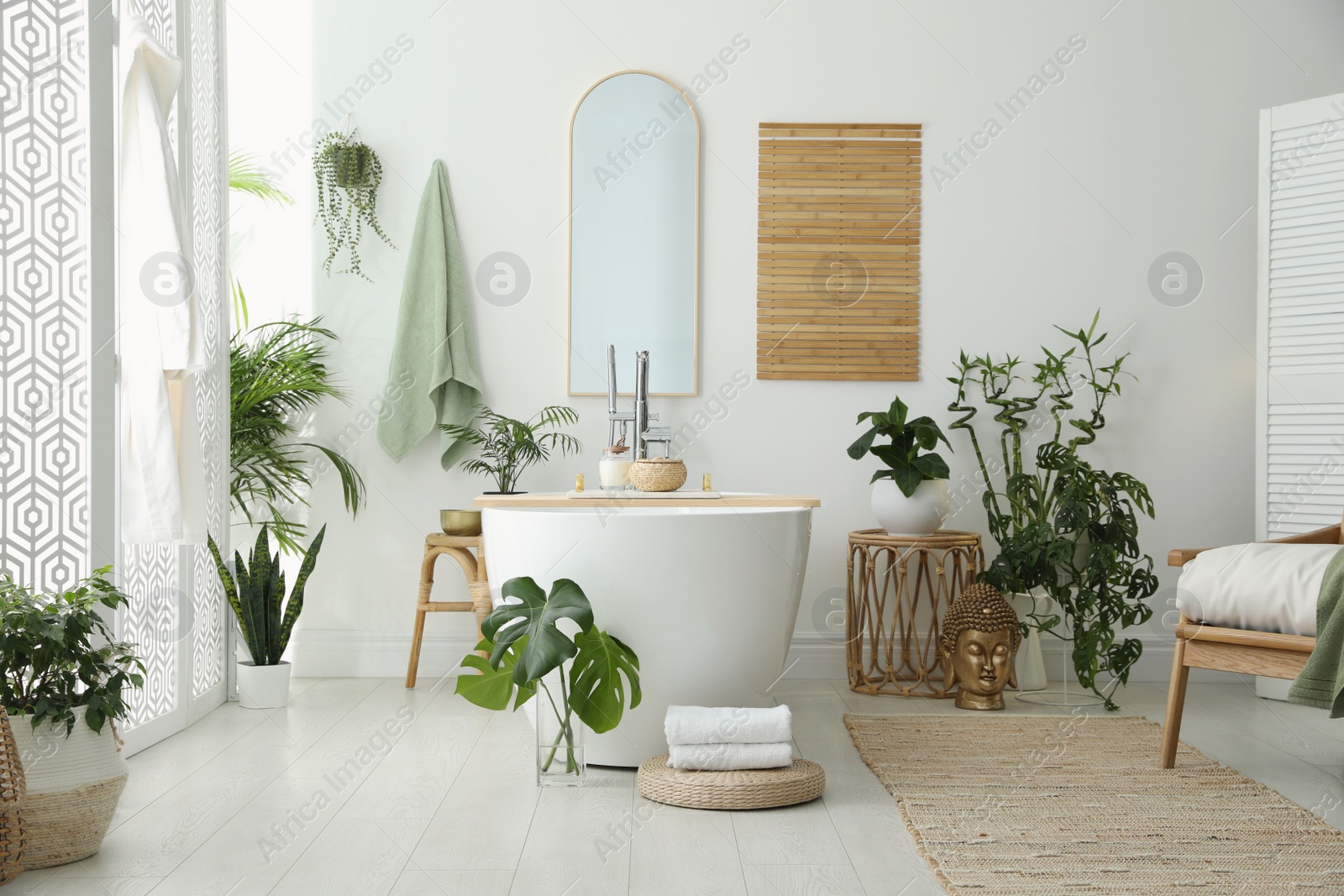 Photo of Stylish bathroom interior with modern tub, houseplants and beautiful decor. Home design