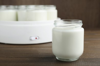 Photo of Glass jar with tasty yogurt on wooden table. Space for text