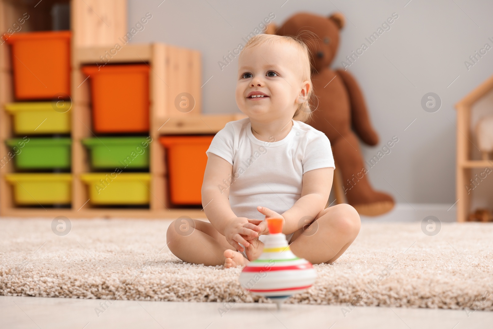 Photo of Children toys. Cute little boy and spinning top on rug at home