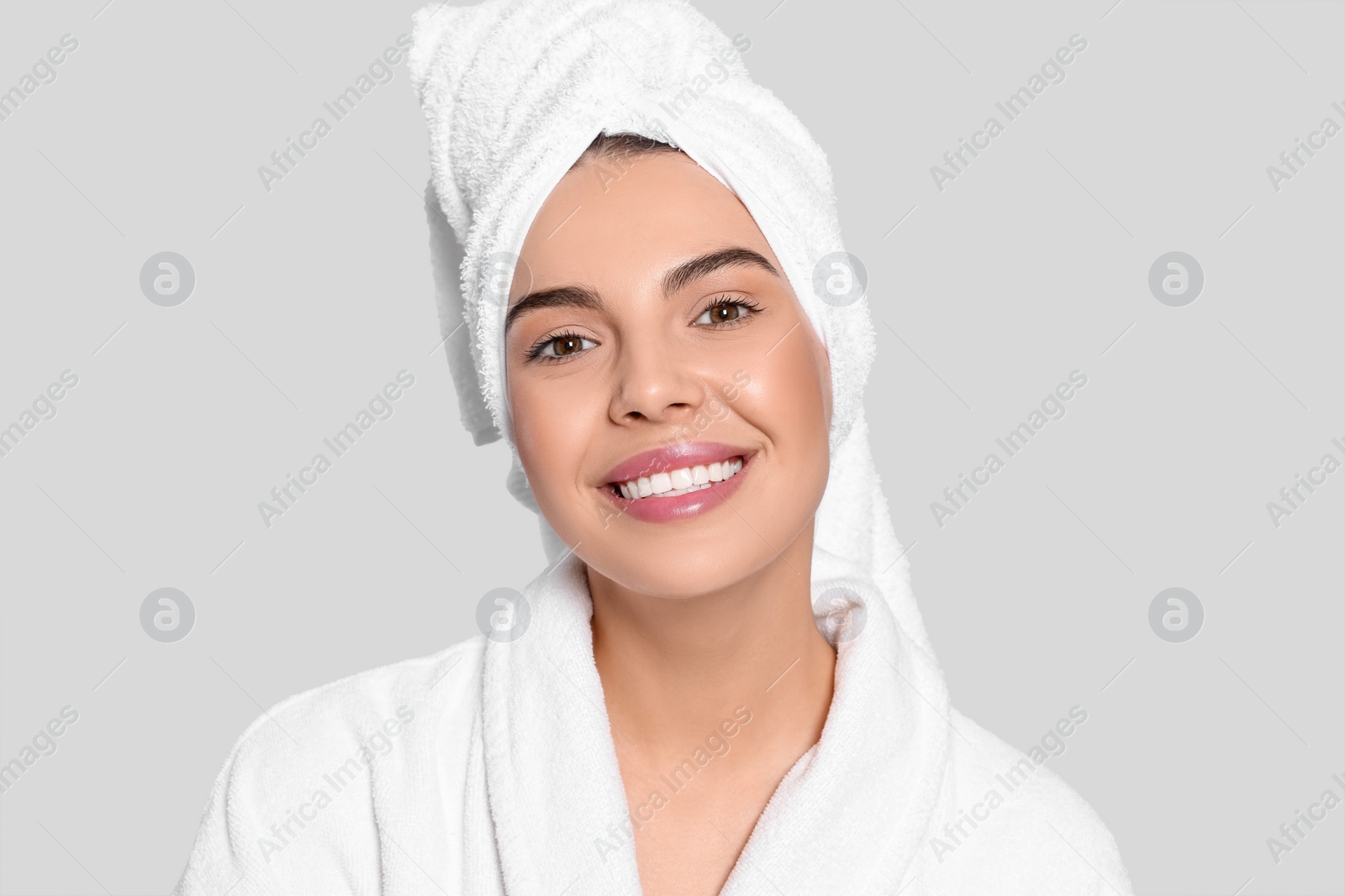 Photo of Young woman in bathrobe with towel on light grey background. Spa treatment