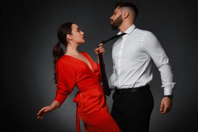 Photo of Handsome bearded man with sexy lady on dark background