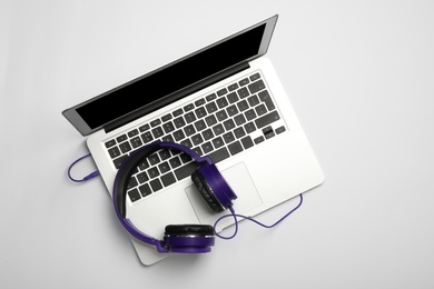 Modern headphones and laptop on white background, top view