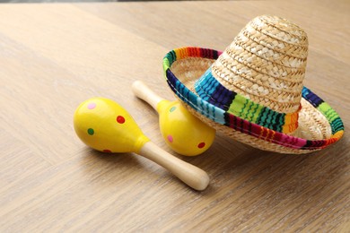 Photo of Mexican sombrero hat and maracas on wooden table