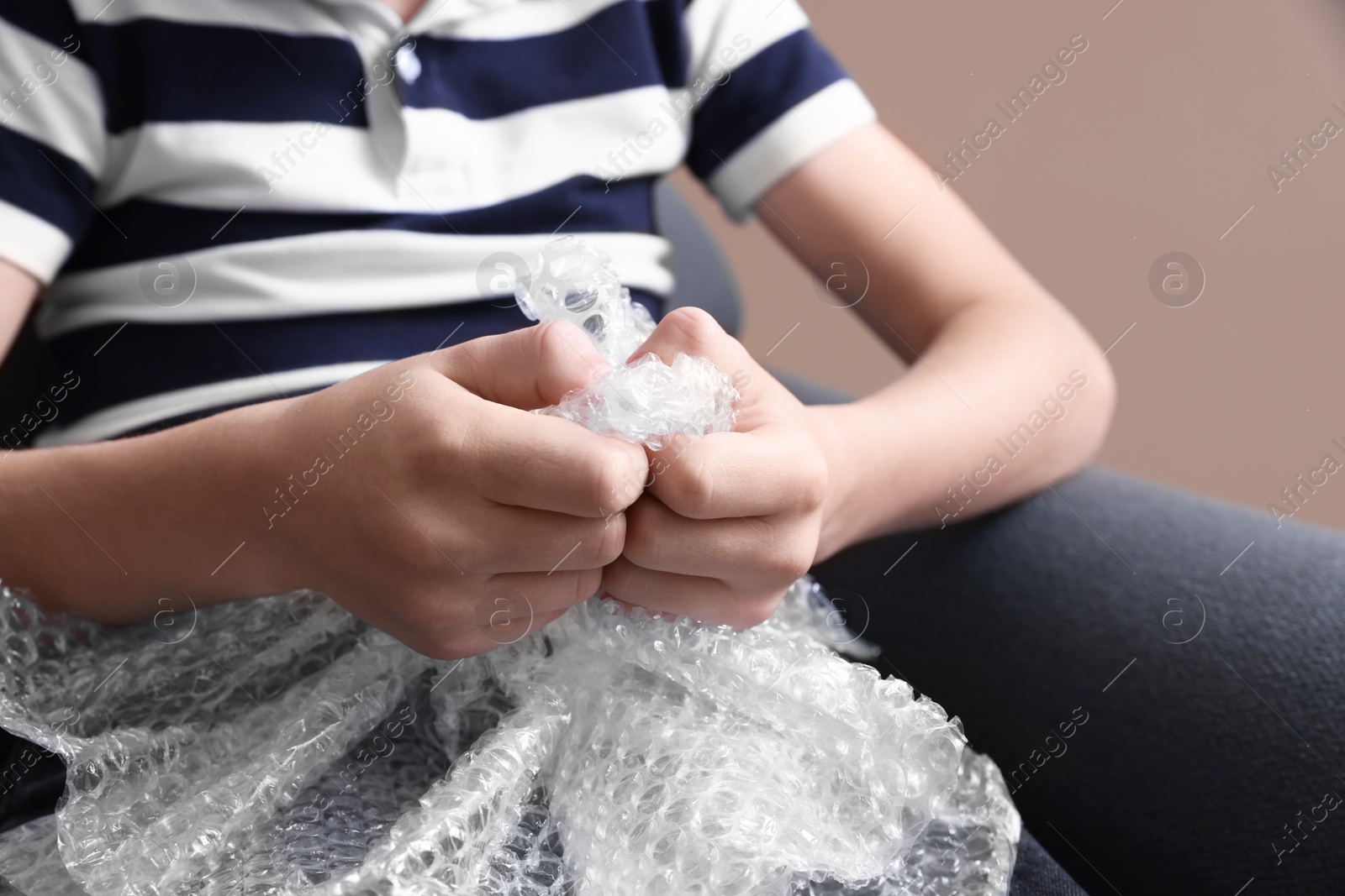 Photo of Boy popping bubble wrap, closeup. Stress relief