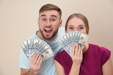 Photo of Happy young couple with money on color background