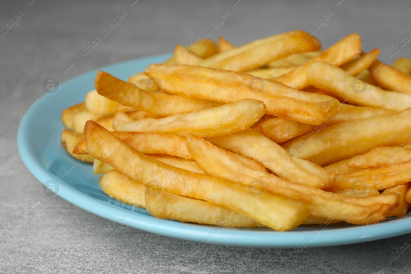 Photo of Turquoise plate with delicious french fries on light gray marble table, closeup