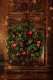 Photo of Beautiful Christmas wreath hanging on wooden door