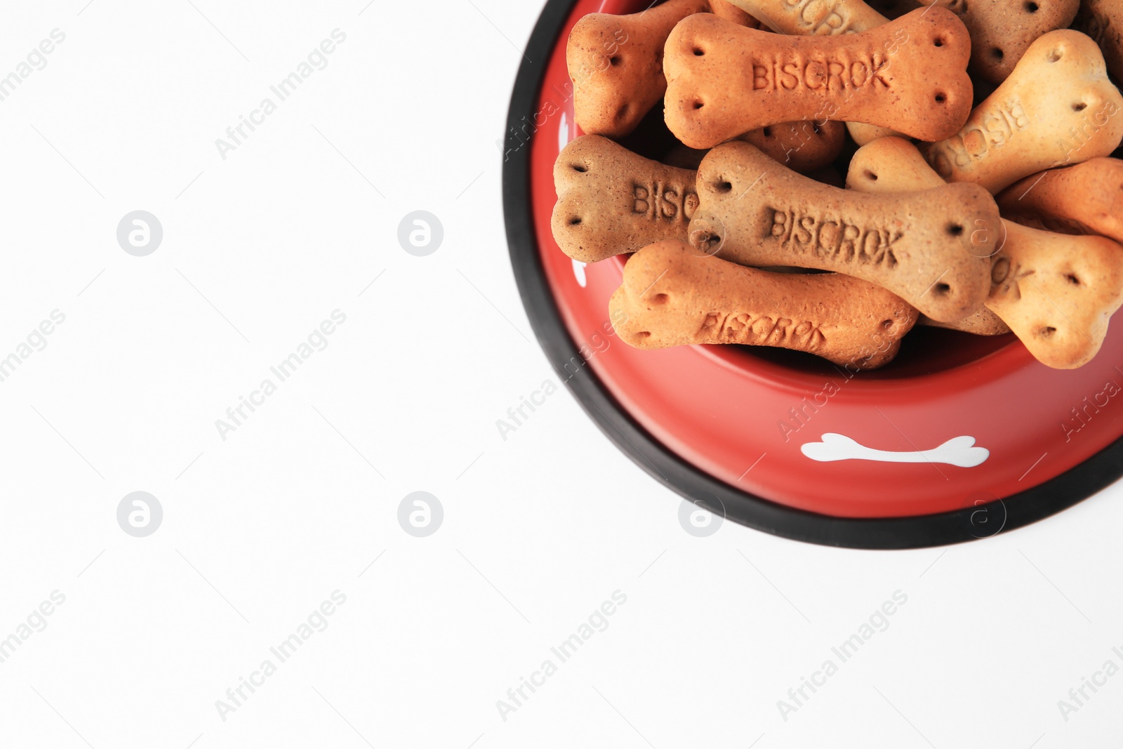 Photo of Bone shaped dog cookies in feeding bowl on white background, top view. Space for text