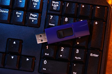 Photo of Modern usb flash drive on computer keyboard, top view