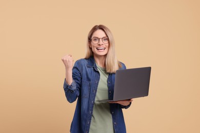 Emotional woman with laptop on beige background