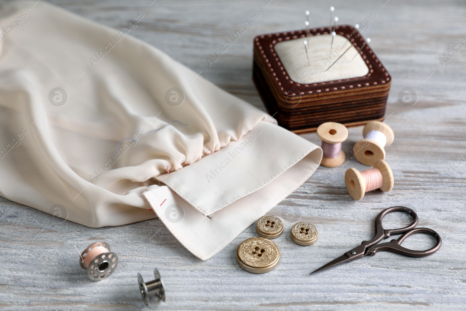 Photo of Set of sewing supplies and accessories with fabric on wooden table