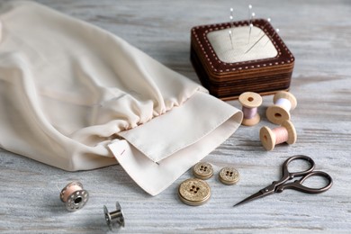 Photo of Set of sewing supplies and accessories with fabric on wooden table