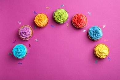 Delicious birthday cupcakes on color background