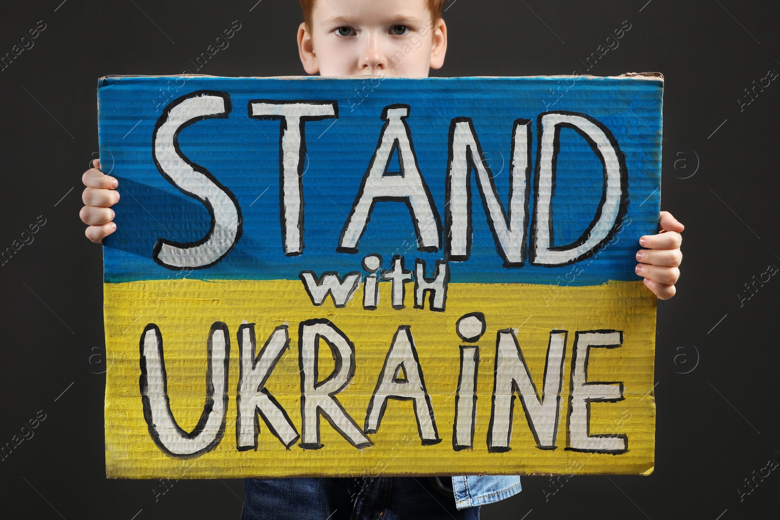 Photo of Boy holding poster Stand with Ukraine against grey background