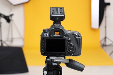 Camera on tripod and professional lighting equipment in modern photo studio, closeup