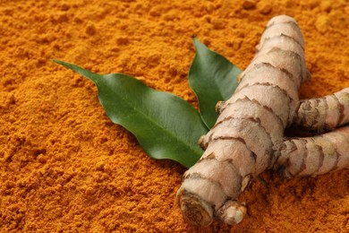 Raw root and leaves on aromatic turmeric powder, closeup. Space for text